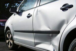 Auto plateado con una abolladura en la puerta trasera. Pasos a seguir después de un accidente de auto