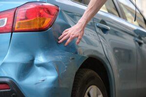 Driver hand examining dented car. Qué hacer después de un accidente con fuga en Las Vegas